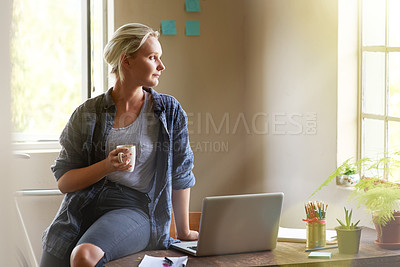 Buy stock photo Shot of a young woman looking thoughtful while sitting on her desk drinking coffee