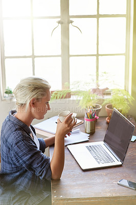 Buy stock photo Shot of a young woman drinking coffee while working at her computer at home