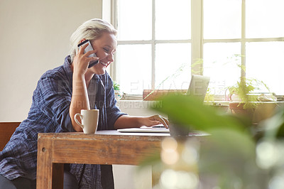 Buy stock photo Shot of a young woman talking on the phone while sitting with her laptop at home
