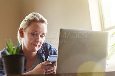 Buy stock photo Shot of a young woman sending a text message while sitting at her laptop at home
