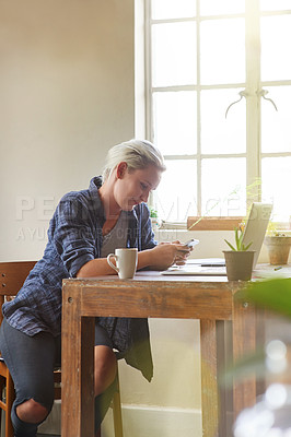 Buy stock photo Shot of a young woman sending a text message while sitting with her laptop at home