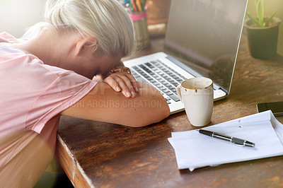 Buy stock photo Shot of a young woman sitting at her laptop with her head resting on her arms