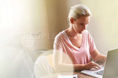 Buy stock photo Cropped shot of a woman working on her laptop with a pen and notebook beside her