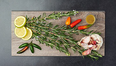 Buy stock photo Herbs, spices and garlic in kitchen on chopping board for wellness, nutrition and health. Organic, vegetables and above lemon on dark background for flavour, cooking and diet for weight loss.