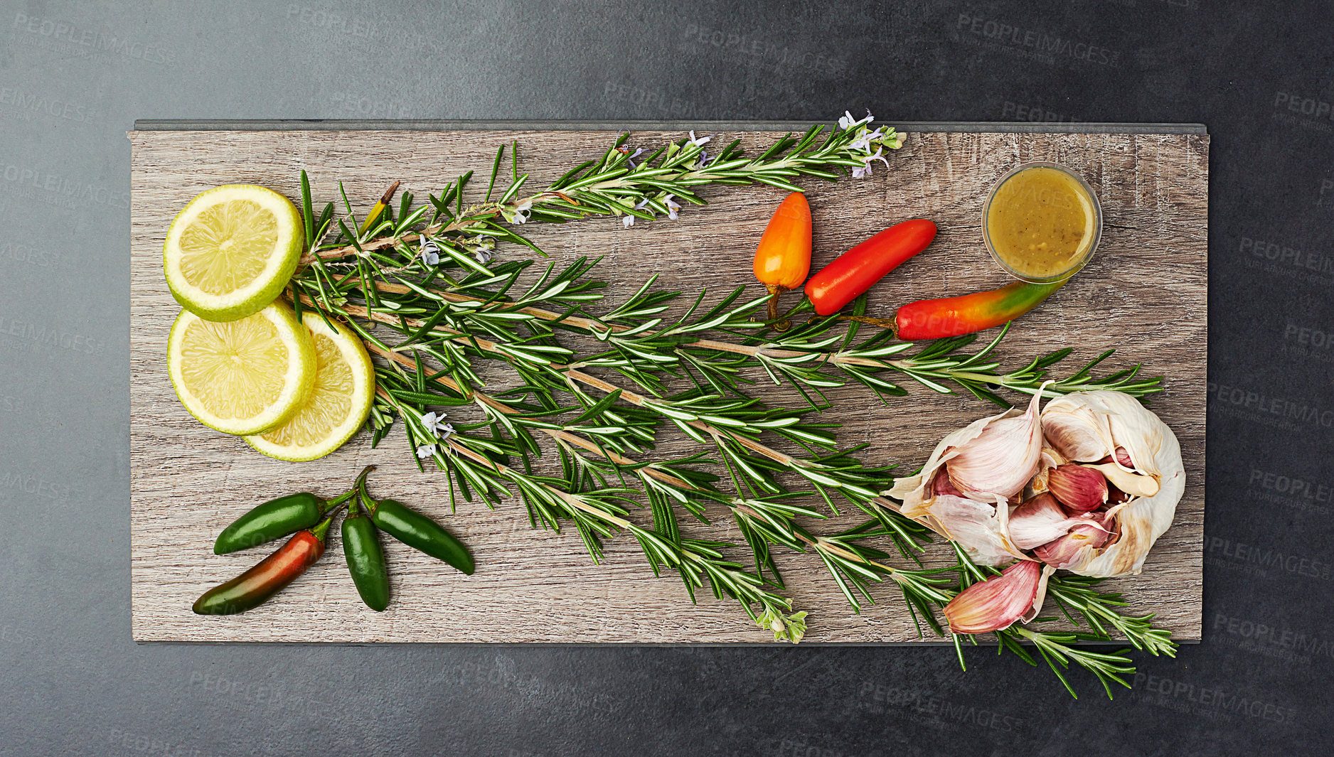 Buy stock photo Herbs, spices and garlic in kitchen on chopping board for wellness, nutrition and health. Organic, vegetables and above lemon on dark background for flavour, cooking and diet for weight loss.