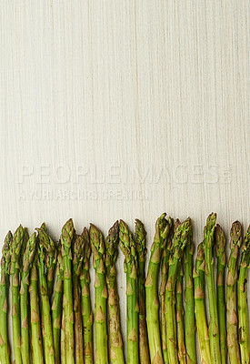 Buy stock photo Cropped shot of green asparagus spears lying on a light wooden surface