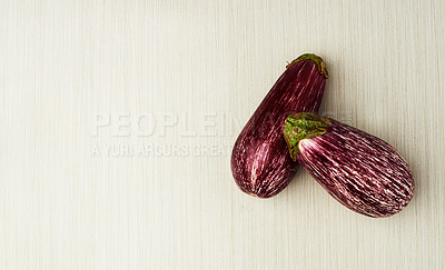 Buy stock photo Eggplant, nutrition and vegan food on table top for wellness, health and diet in studio. Aubergine, green and purple isolated for eating, ingredients and mockup space in house for above and cook.