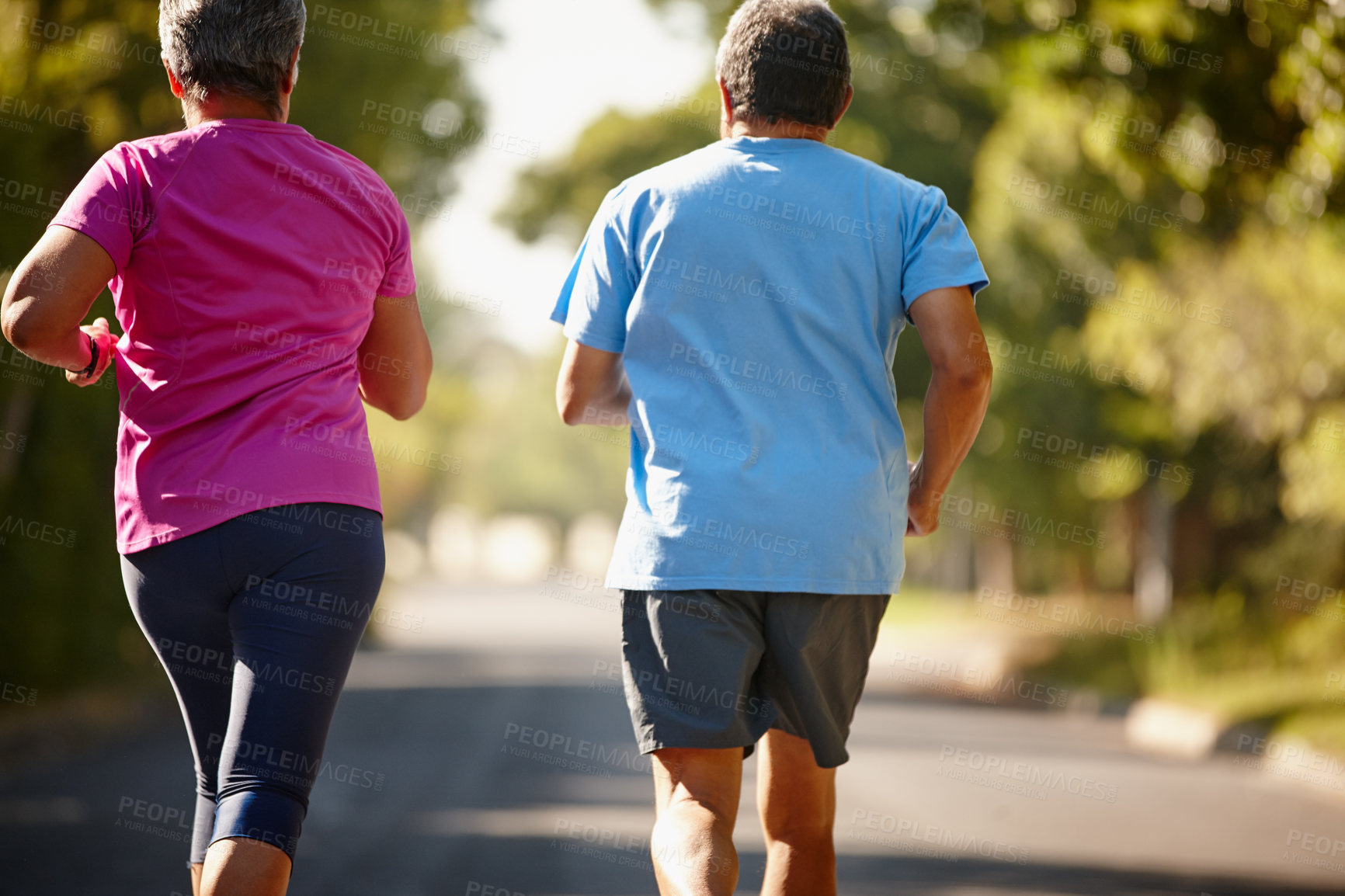 Buy stock photo Rearview shot of a mature couple jogging together on a sunny day