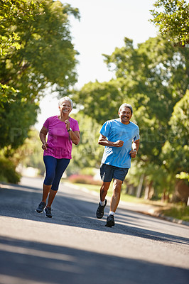 Buy stock photo Shot of a mature couple jogging together on a sunny day