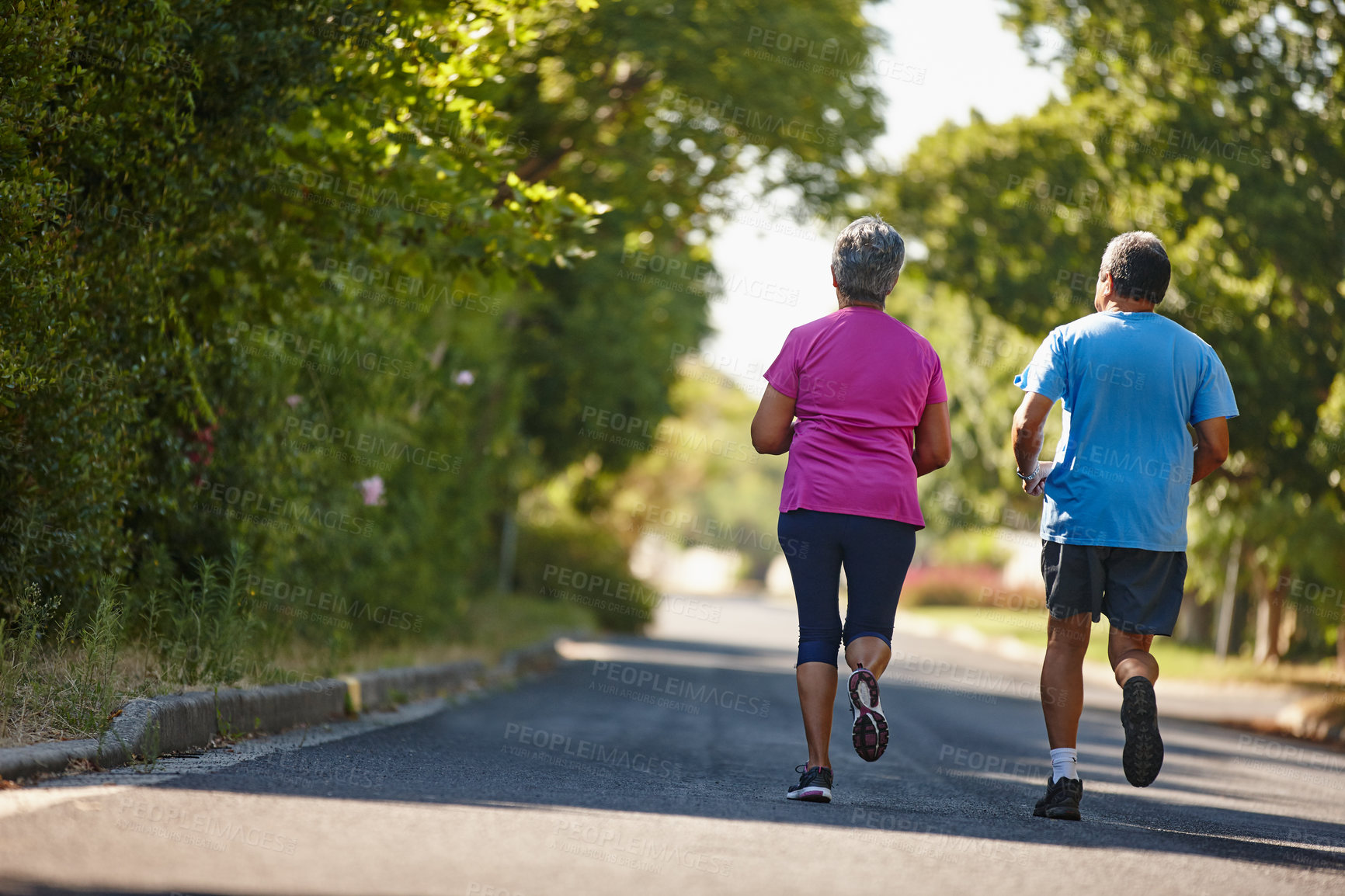 Buy stock photo Rearview shot of a mature couple jogging together on a sunny day