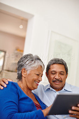 Buy stock photo Shot of a happy senior couple using a digital tablet together at home