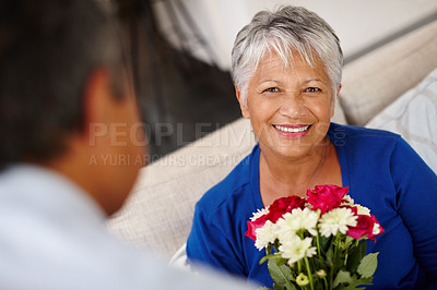 Buy stock photo Shot of a happy senior woman receiving a bunch of flowers from her husband