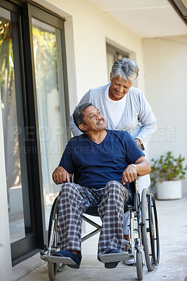 Buy stock photo Shot of a senior woman pushing her husband in a wheelchair outdoors