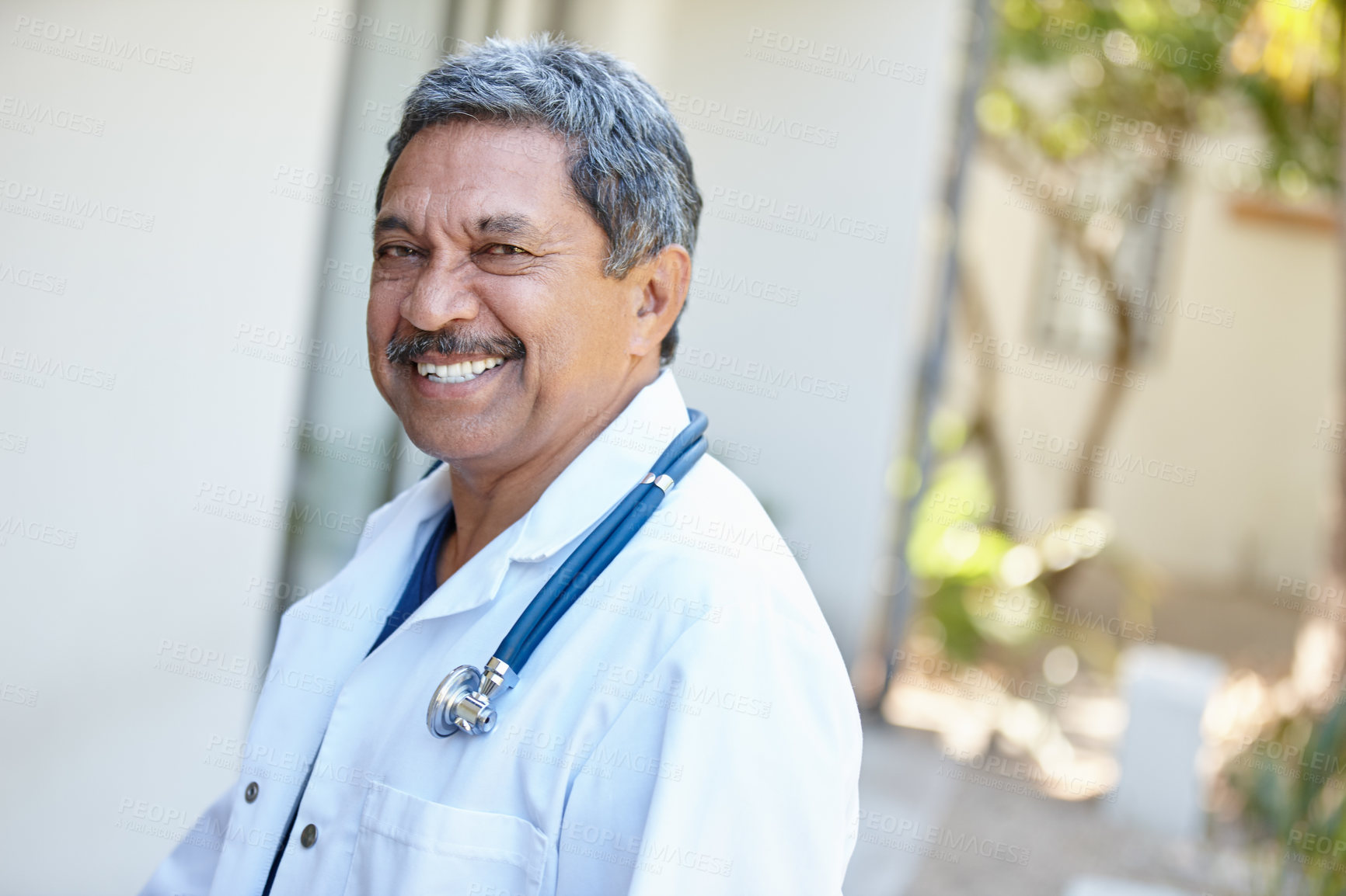Buy stock photo Cropped portrait of a male doctor smiling happily outside