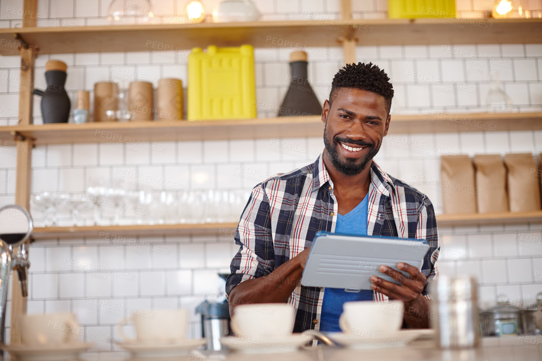 Buy stock photo Cropped shot of a coffee shop owner using a tablet while working in his cafe