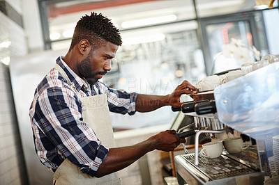 Buy stock photo Shot of a handsome male barista making a cup of coffee using an espresso machine