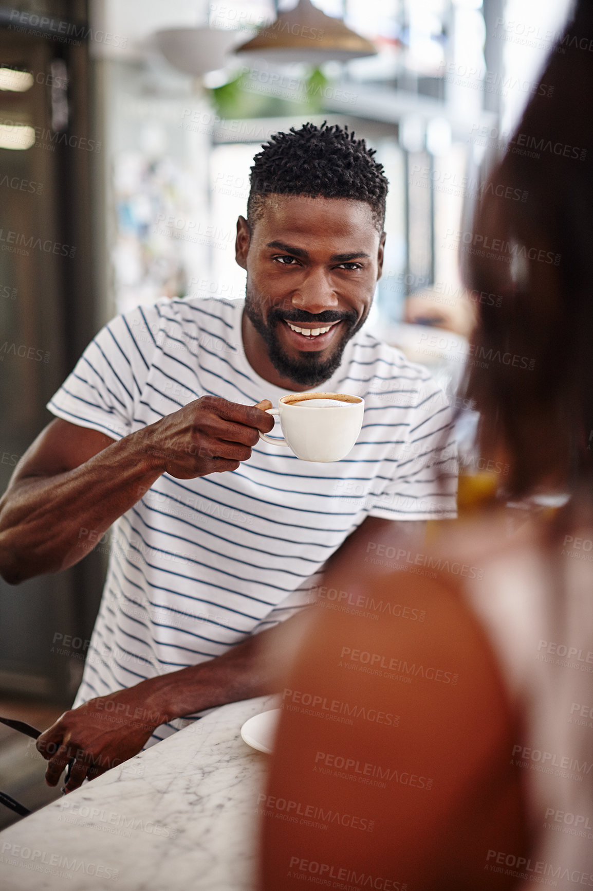 Buy stock photo A young man drinking a cup of coffee at a cafe counter