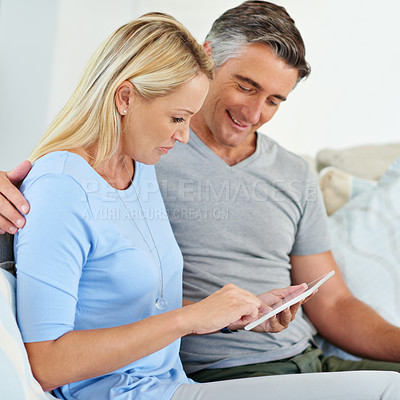 Buy stock photo Shot of a mature couple sitting at home using a digital tablet
