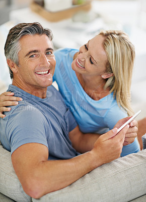 Buy stock photo Portrait of a laughing couple sitting at home using a digital tablet