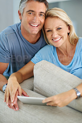 Buy stock photo Portrait of a smiling couple sitting at home using a digital tablet