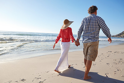 Buy stock photo Shot of a mature couple enjoying a late afternoon walk on the beach