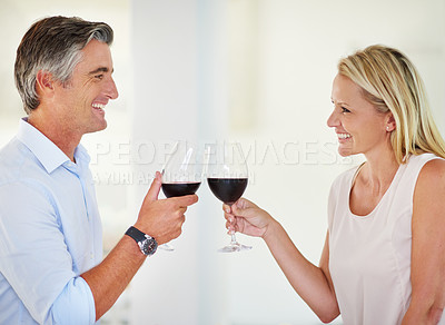 Buy stock photo Shot of an affectionate couple toasting with red wine