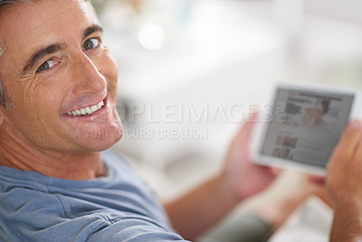 Buy stock photo Portrait of a handsome mature man using a digital tablet while relaxing at home