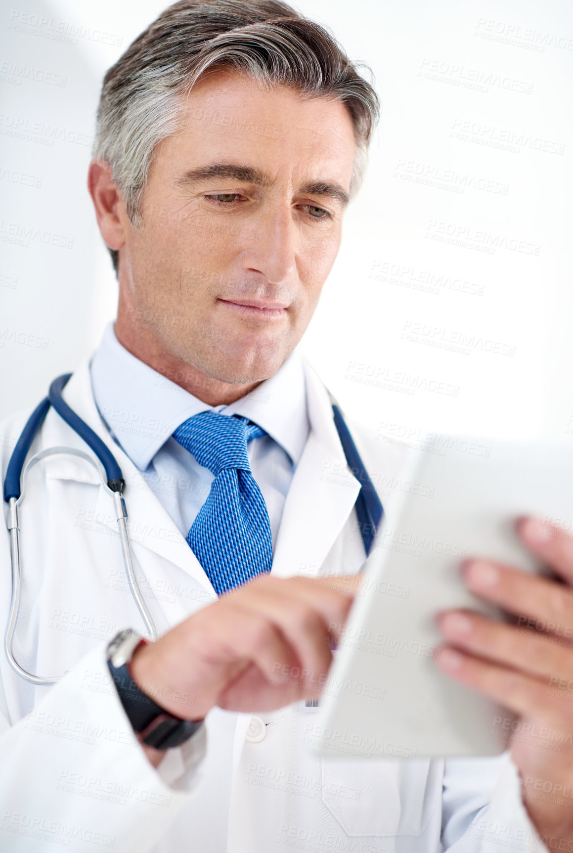 Buy stock photo Doctor, man and research on tablet for information, telehealth or healthcare in hospital. Digital technology, medical professional and reading email on app for report or clinic results in low angle