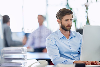 Buy stock photo Shot of a handsome young businessman working at his office computer