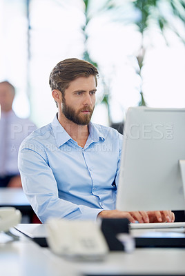Buy stock photo Shot of a handsome young businessman working at his office computer