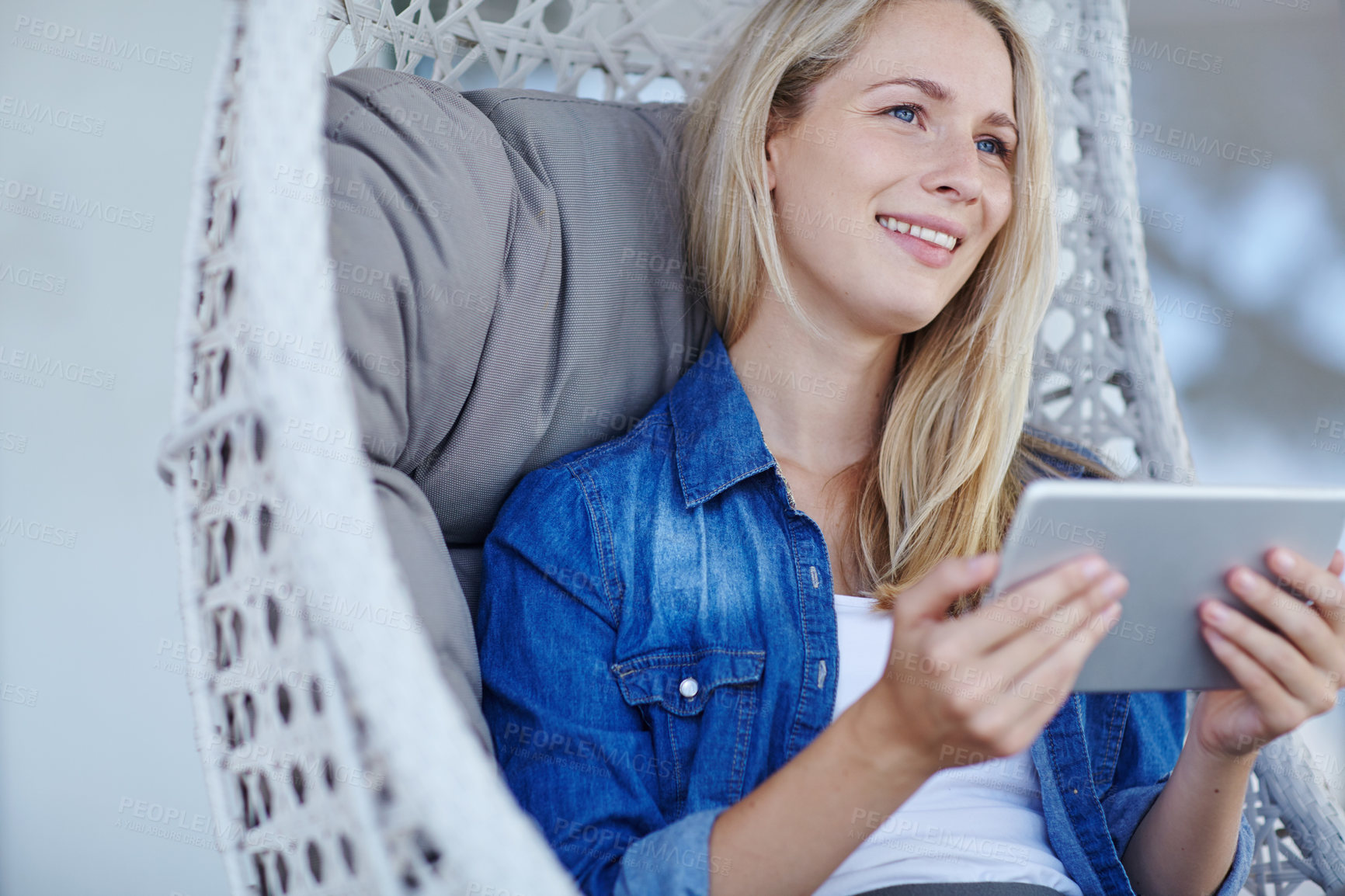 Buy stock photo Shot of an attractive young woman relaxing in a hanging basket chair on her patio