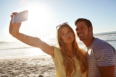 Buy stock photo Cropped shot of an affectionate young couple taking a selfie on the beach