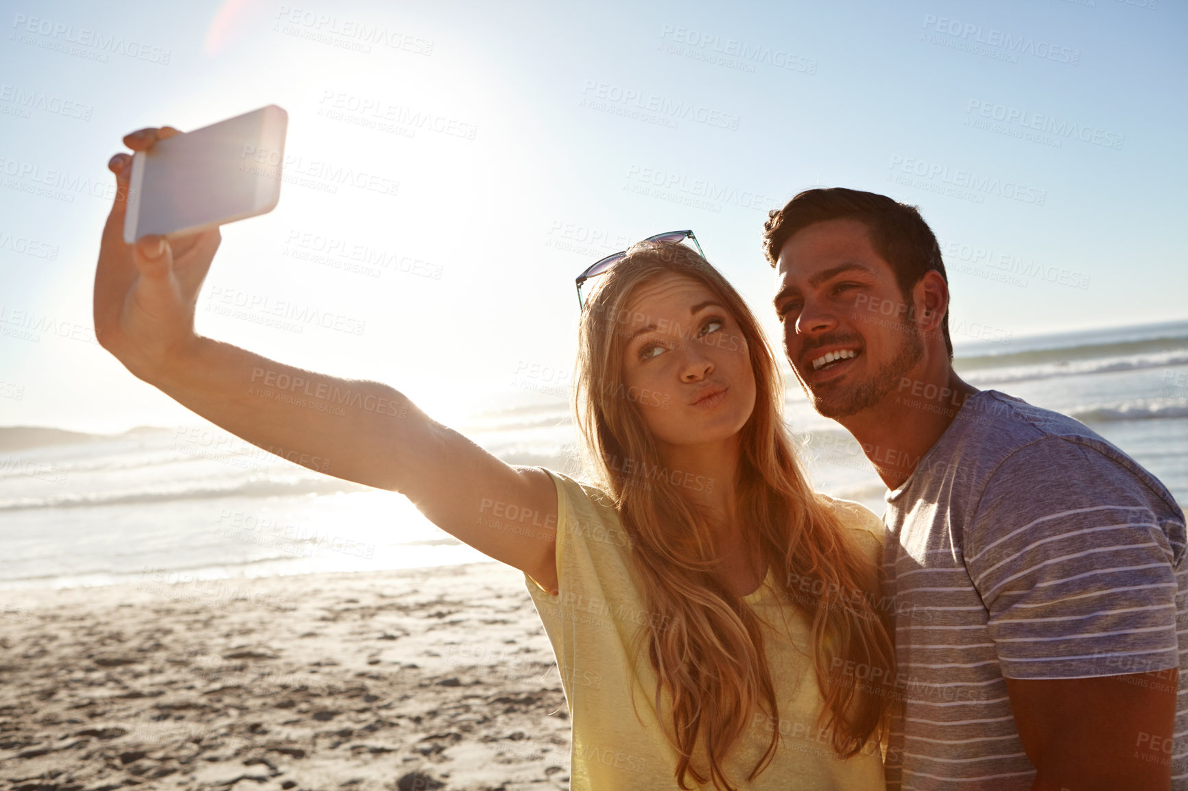 Buy stock photo Cropped shot of an affectionate young couple taking a selfie on the beach