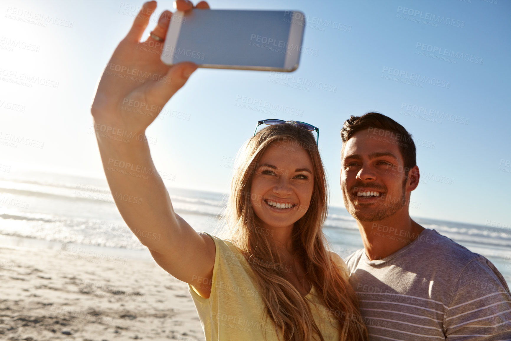 Buy stock photo Cropped shot of an affectionate young couple taking a selfie on the beach