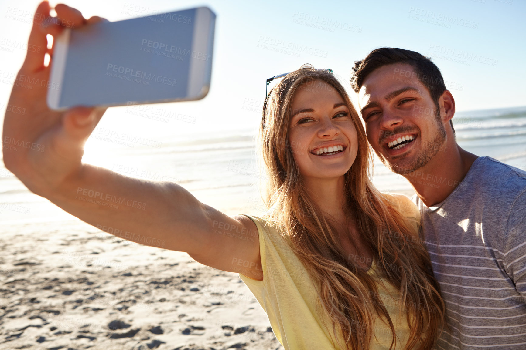 Buy stock photo Cropped shot of an affectionate young couple taking a selfie on the beach