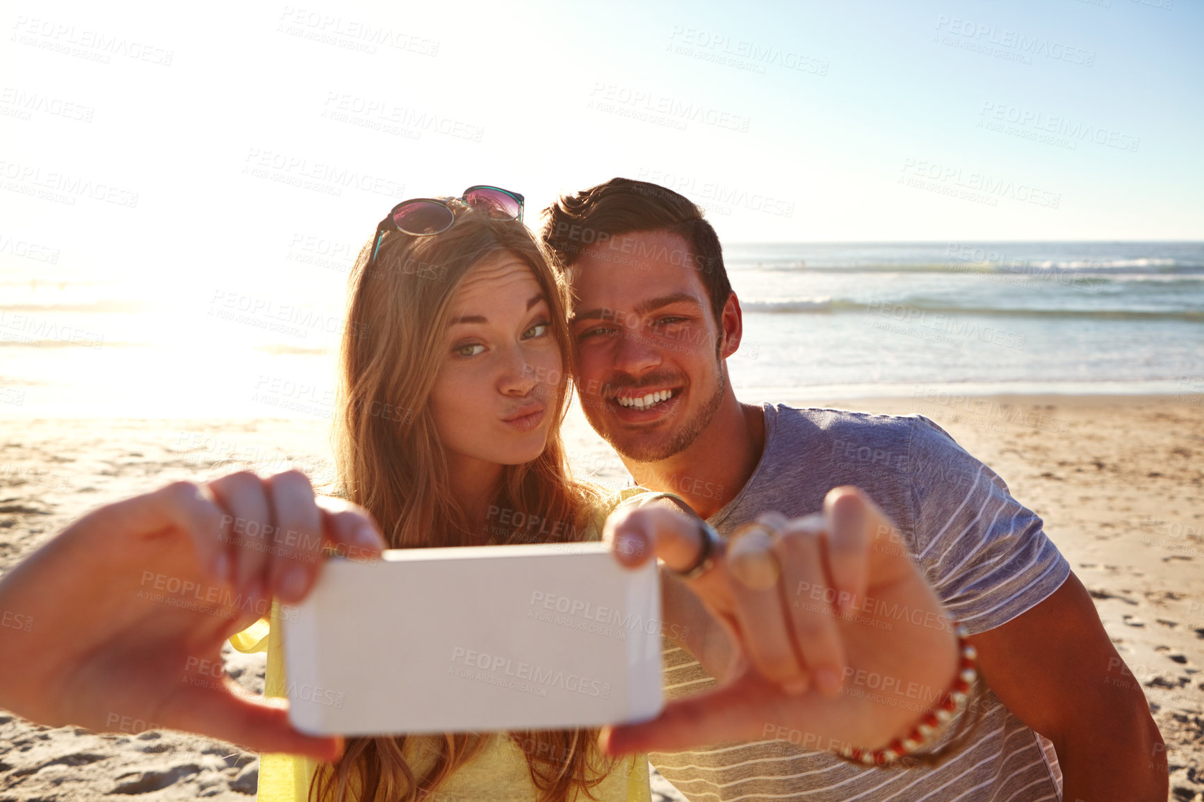 Buy stock photo Cropped shot of an affectionate young couple taking a selfie on the beach