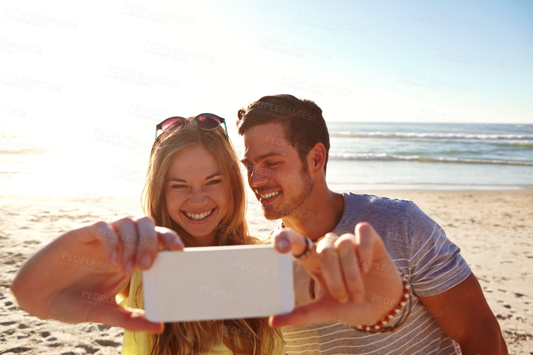 Buy stock photo Cropped shot of an affectionate young couple taking a selfie on the beach