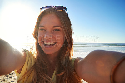 Buy stock photo Cropped shot of an attractive young woman taking a selfie on the beach