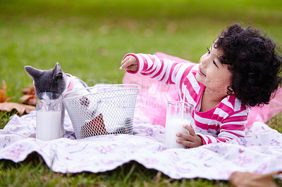 Buy stock photo Milk, picnic and a girl in the park with her kitten together for love, care or bonding during summer. Smile, cat or kids playing and a cute young child in the garden having fun with her pet animal