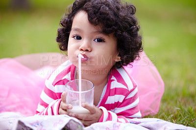 Buy stock photo Portrait, child and glass of milk on grass while lying down with satisfaction on face for beverage. Little girl, pink tutu and curly hair for development for health, nutrition and calcium for growth