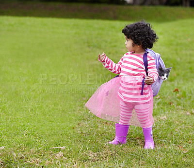 Buy stock photo Nature, kitten and girl child with backpack walking on grass in outdoor garden in summer. Confused, backyard and young kid with childhood playing on the lawn with cat in field or park in countryside.