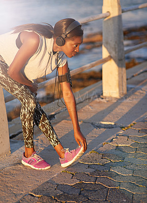 Buy stock photo Woman, headphones and stretching on beach outdoor with cardio performance, sports workout and fitness. Girl, runner and warm up with exercise, marathon training and listening to music for competition