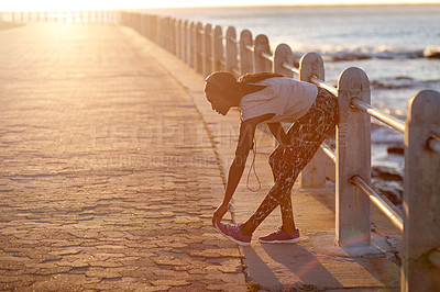 Buy stock photo Athlete, girl and stretching on beach outdoor with cardio performance, sports workout and fitness. Woman, runner and sunset with headphones, marathon training and listening to music for competition