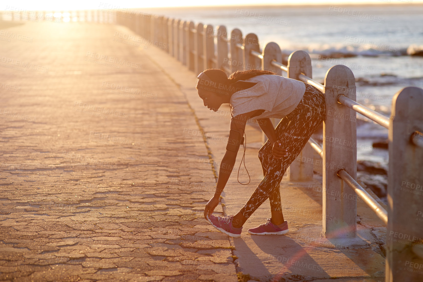 Buy stock photo Athlete, girl and stretching on beach outdoor with cardio performance, sports workout and fitness. Woman, runner and sunset with headphones, marathon training and listening to music for competition