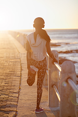 Buy stock photo Back, woman and stretching on beach outdoor for cardio performance, sports workout and fitness goal. Girl, runner and warm up with headphones, marathon training and listening to music for competition