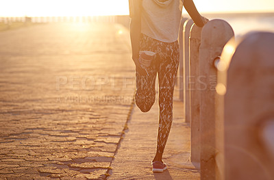 Buy stock photo Cropped image of a young woman stretching her legs while out for a run