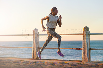 Buy stock photo A young woman running along the promenade at sunset