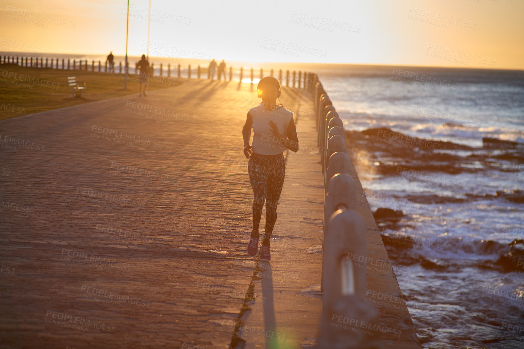 Buy stock photo A young woman running along the promenade at sunset