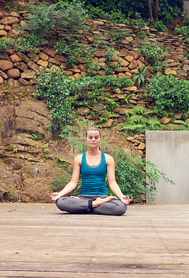 Buy stock photo Shot of a young woman practicing yoga outdoors