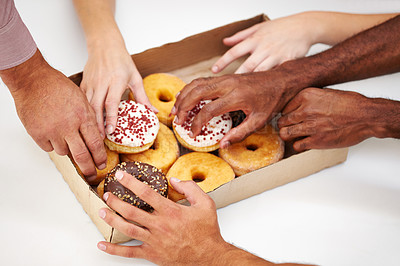 Buy stock photo A multitude of hands reaching to grab a doughnut from a box